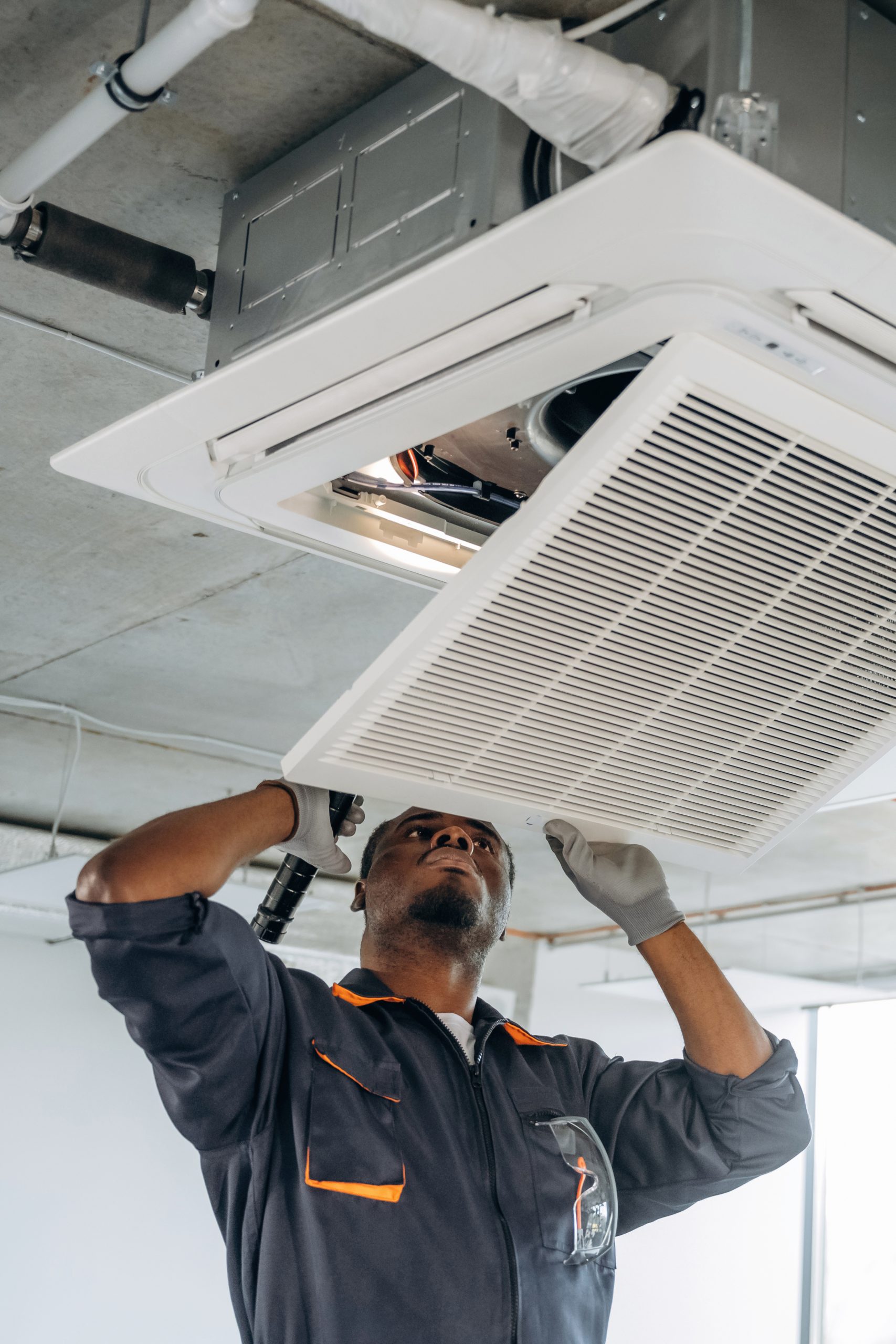 Broken ventilation, fixing it. Repairman is indoors in the modern office